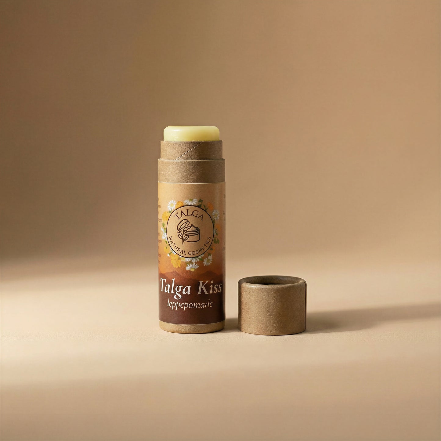 Talga Kiss leppepomade lip balm with the cap off and balm stick exposed on a beige background.